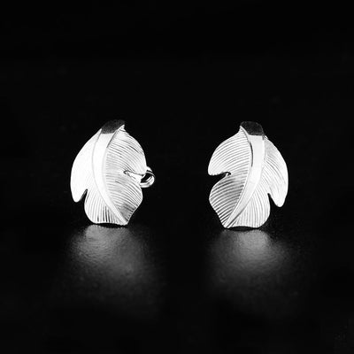 Sterling Silver Owl Feather Stud Earrings by Fred Myra. Each earring is in the shape of a very small feather. The artist has hand-carved intricate designs that representing the delicate, wispy texture of a feather on each earring.