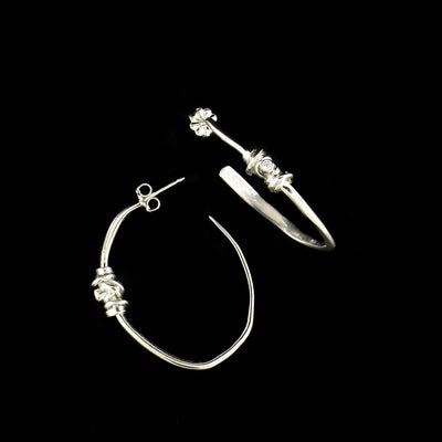 Sterling Silver Wavy Coil with Cubic Zirconia Hoop Earrings by Joy Annett. The earrings are made entirely of sterling silver with cubic zirconia accents in the center of each earring.