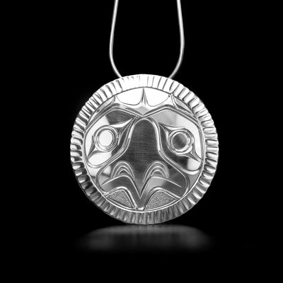 Sterling Silver 2" Round Eagle Pendant by Paddy Seaweed. The design depicts the face of an eagle looking straight forward. The perimeter of the pendant has been delicately carved to create a smooth, feather-like texture.