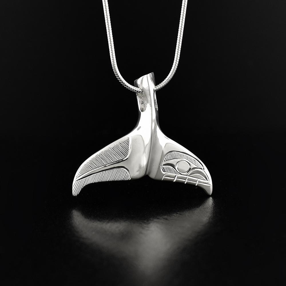 This sterling silver whale tail pendant is shaped like the tail of a whale and has a depiction of the Orca carved into the surface of the fin.