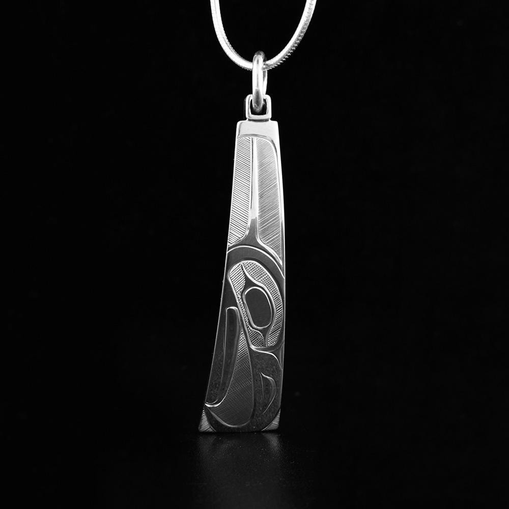 This sterling silver Eagle pendant is long and tapers outward slightly. There is a depiction of the Eagle carved into the surface of the piece.