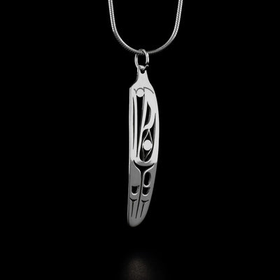This raven pendant is in the shape of a feather and depicts the head of a raven with a small ball in its beak facing upward. There are carved feathers behind the head of the raven.