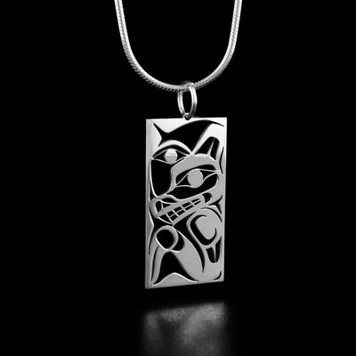 This wolf and moon pendant depicts the profile of a wolf's head with a paw underneath. The artist has included half of a moon's face in the background.