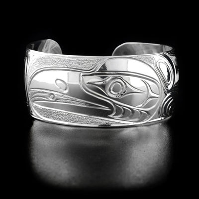 Sterling Silver 1" Raven Bracelet by Paddy Seaweed. The design depicts the profile of a raven's head facing the left with his tongue sticking out. The artist has carefully handcarved the background so the raven stands out. On the sides are intricate designs.
