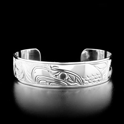 This eagle bracelet has the profile of an eagle's head facing the left in the center of the bracelet. To the left is a forest and to the right is the eagle's wing.