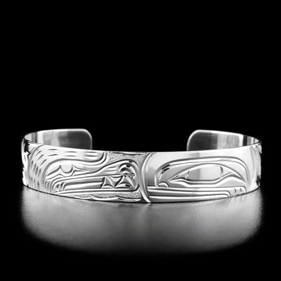 The center of this cuff bracelet has the profile of a bear's head on the left facing the profile of an orca's head on the right.
