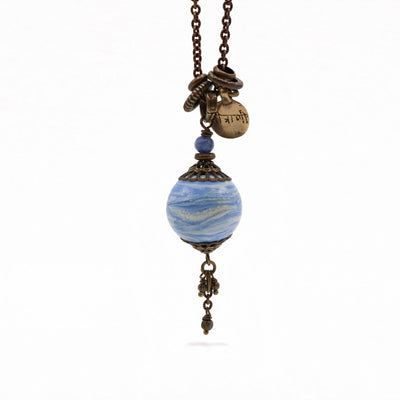 This Vanilla Blue Pendant is handcrafted by artist Wendy Pierson. She has used her handmade lampworked glass for the pendant and antique brass for the chain and adornments. The necklace is 29.25" long and the pendant measures 2.4" x 0.75" including the bail.
