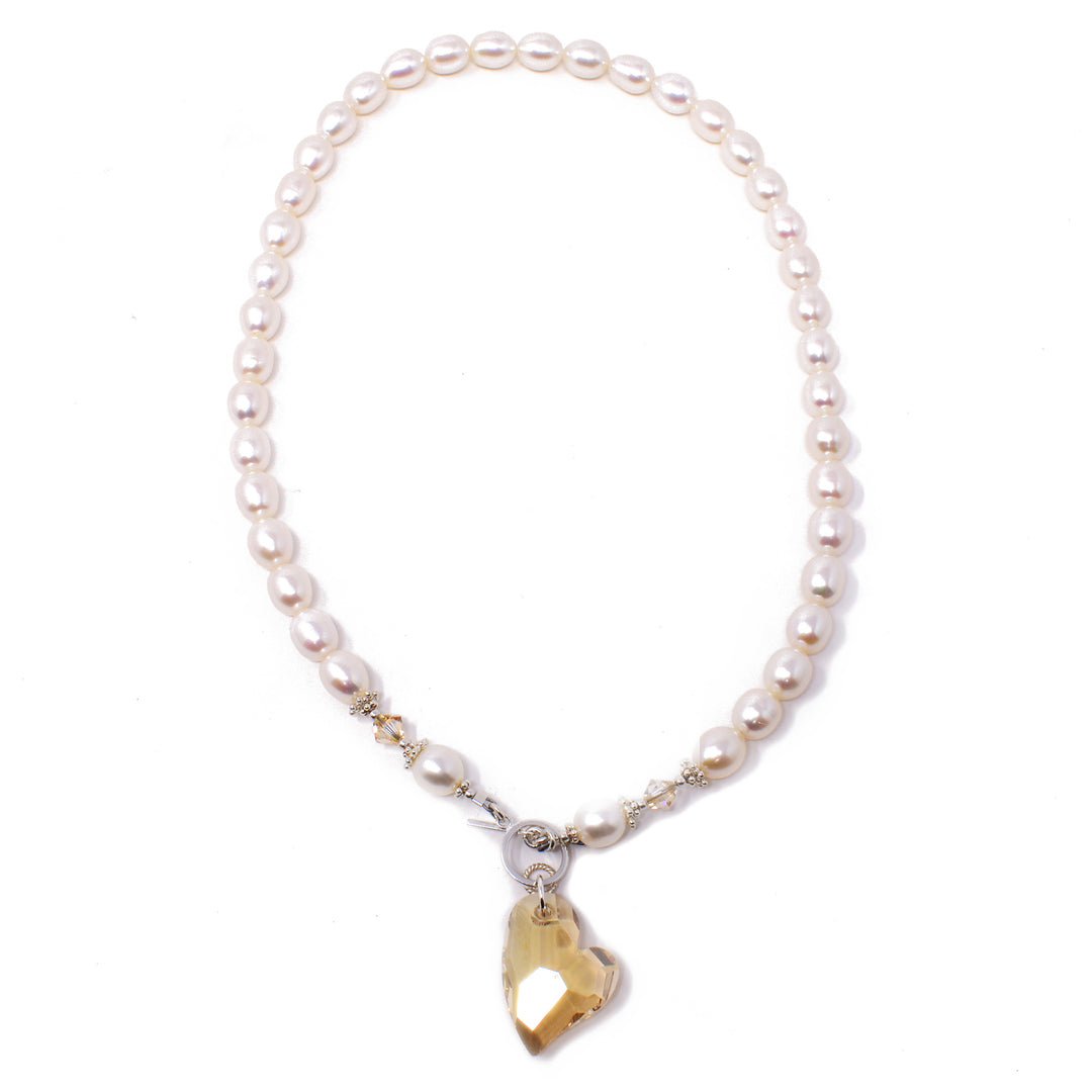 This Crystal and Pearl Sweetheart Necklace is handcrafted by artist Karley Smith. She has used freshwater pearls, Swarovski crystal, and sterling silver to create this piece. The necklace is 18" long and the pendant measures 1.50" x 0.75", including the toggle clasp.
