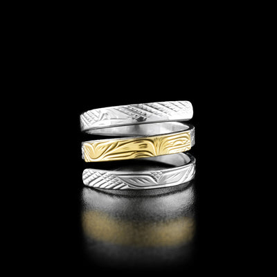 The middle layer of this triple wrap ring depicts the profile of a full-bodied orca made out of gold. The other two layers are made from silver and have carvings of additional whale tails and fins.