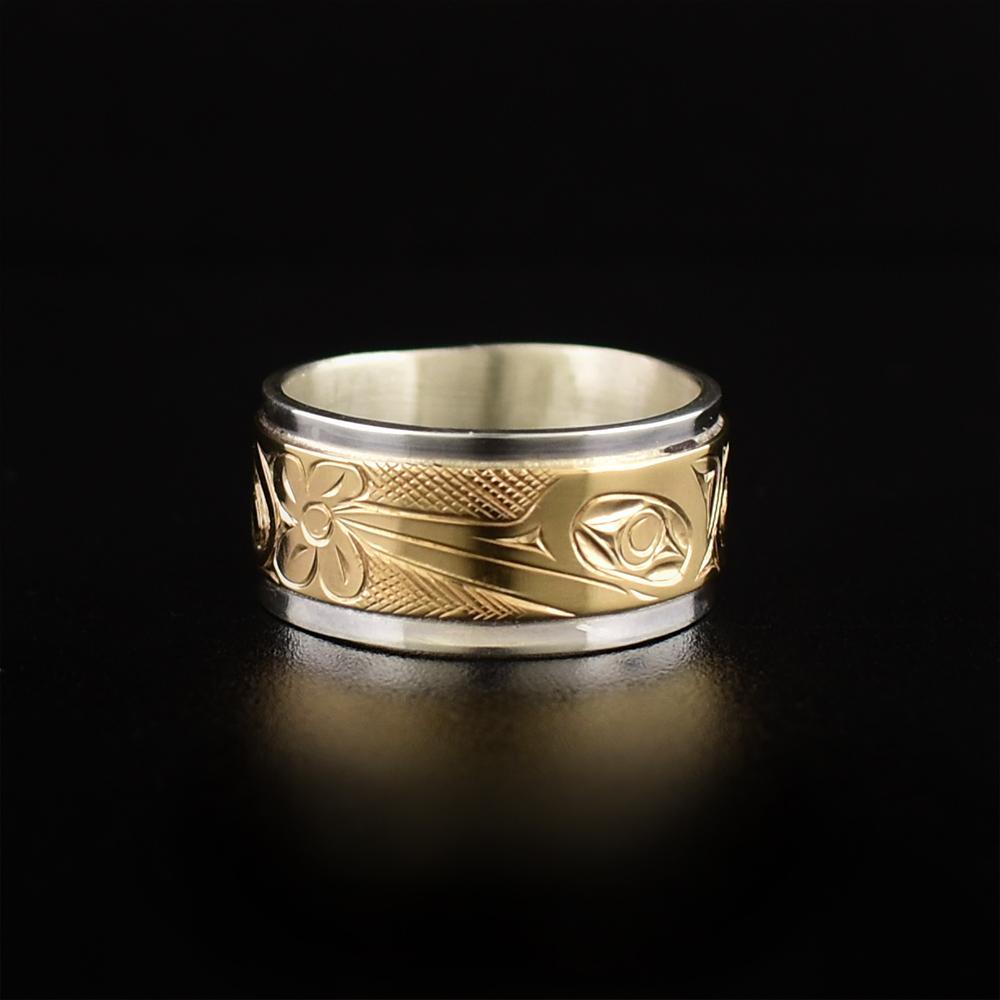 This gold Hummingbird ring is made from sterling silver and 14K gold and has a single, wide ring. There is a large gold band over top of a silver band and there is a depiction of the Hummingbird carved into the gold section of the band.