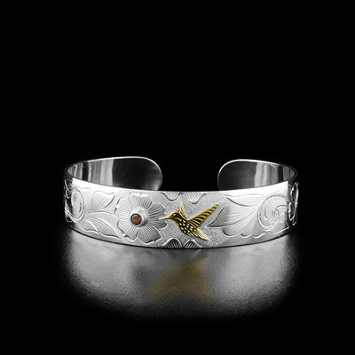 The center of this hummingbird bracelet has a hummingbird made out of 10k yellow gold mid-flight drinking from a flower. The flower has a garnet set in the center.