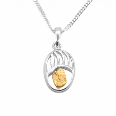 22K Gold Nugget Oval Bear Paw Pendant by Tom Gregorczyk. The pendant is an oval shape and has been carved to resemble the paw of a bear. The artist has put a 22k gold nugget in the bottom center of the pendant.