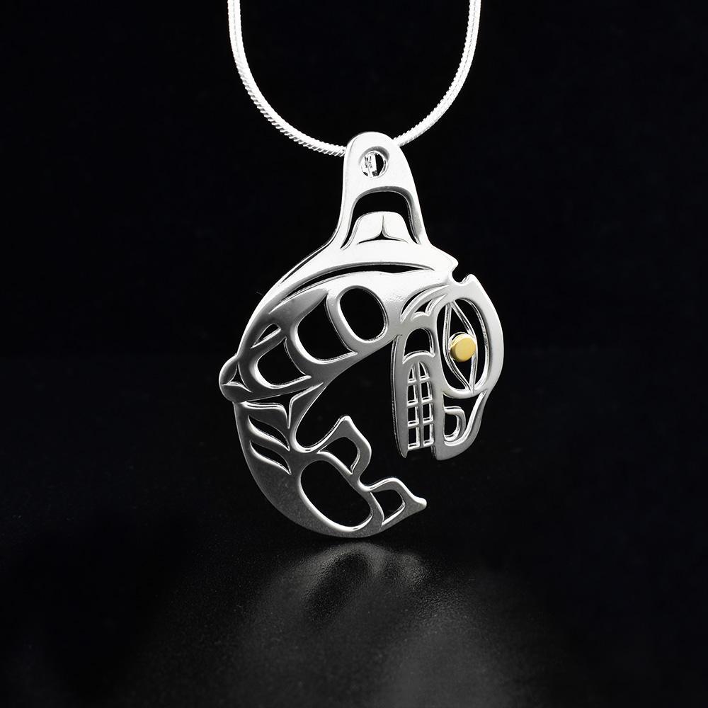 This beautiful Orca pendant is made form sterling silver and 18K gold and is shaped like the Orca at the peak of its leap out of the water. There are cutout designs in the pendant that depict the Orca and the eye of the Orca is made from gold.