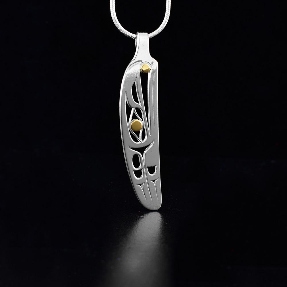 This Raven feather pendant is made from sterling silver and 18K gold. The pendant is feather shaped and has cutout designs that depict the Raven and its eyes are made from gold.