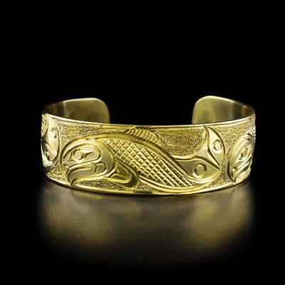 Brass Salmon Bracelet by Paddy Seaweed. The design depicts the profile of three full-bodied salmon swimming across the bracelet. The background has been carefully hand carved to allow for the legend to stand out.