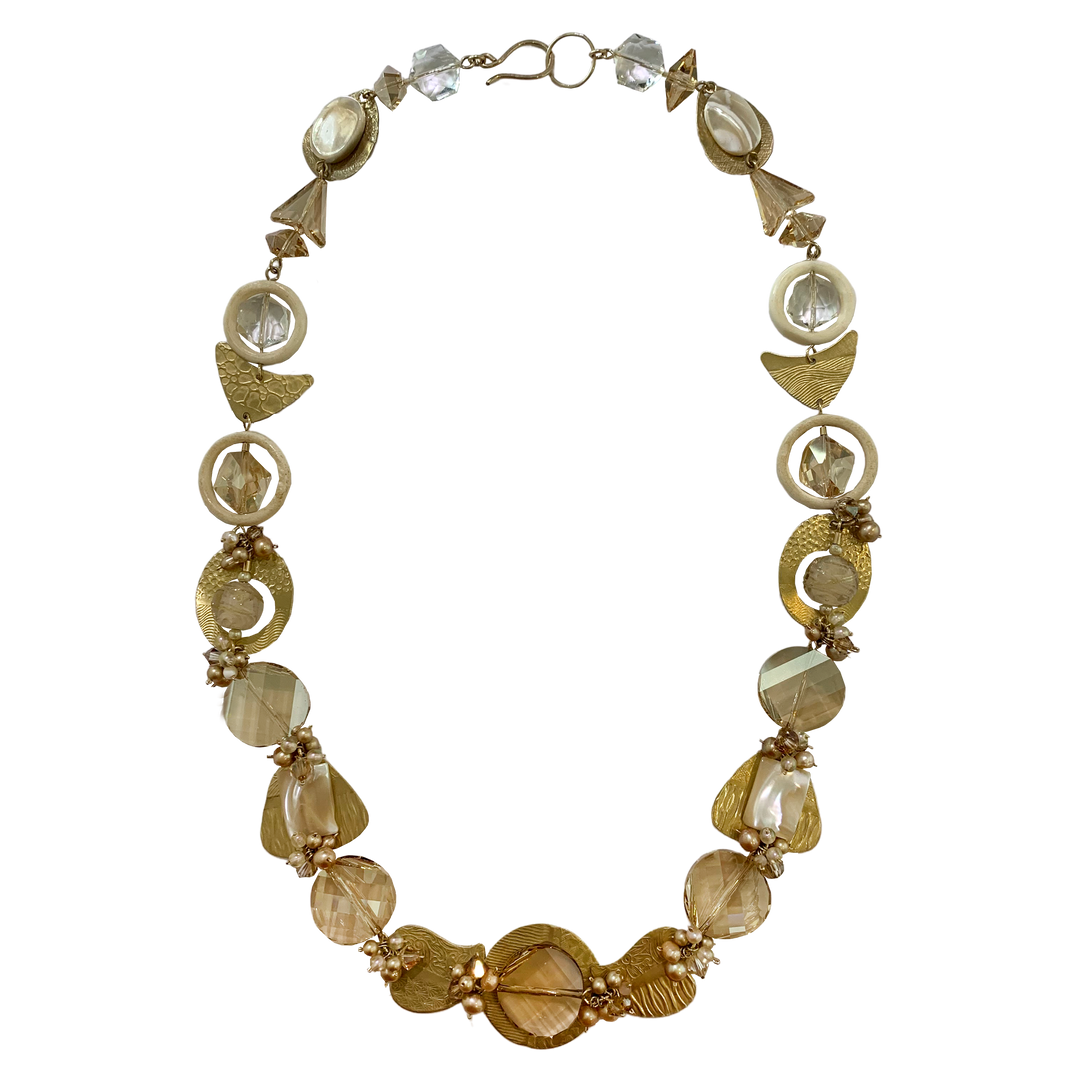 This unique pearl and crystal necklace is made from hand worked brass, Austrian crystals, freshwater pearls and glass. The necklace features many chain links and beads of different shapes and materials running along the necklace.