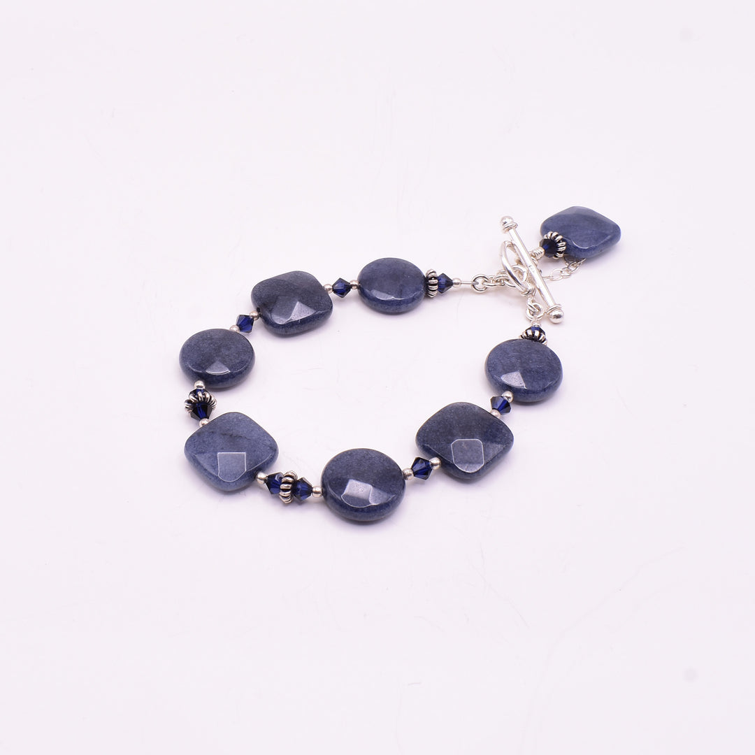 Dazzling blue jade bracelet handcrafted by artist Karley Smith. She used sterling silver, blue jade and Swarovski Crystal to create this piece. Bracelet is 8" long when clasped shut.