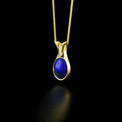 Stunning lapis lazuli pendant handcrafted by artist Dennis Kangasniemi. He has set lapis lazuli in 14K yellow gold. Above the lapis lazuli is a Canadian diamond in a 14K white gold bezel setting. Pendant measures 0.81" x 0.38". Chain not included.