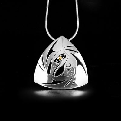 Pierced Gold and Silver Triangle Raven Pendant by Tahltan artist Grant Pauls. There is 18K gold in the eye of the raven, the rest of the piece is done in sterling silver. Pendant measures 1.30" x 1.26". Hidden bail on back. Chain not included.