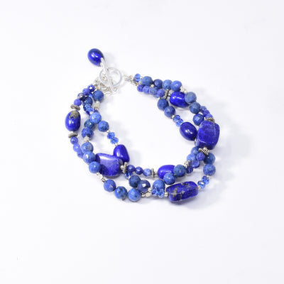 Dazzling blue braided bracelet handcrafted by artist Karley Smith. She has used sterling silver, oxidized silver, Swarovski Crystal, lapis lazuli and sodalite to create this piece. Bracelet closes with a toggle clasp and a safety chain adds an extra element of security. Bracelet is 8" long when clasped shut.