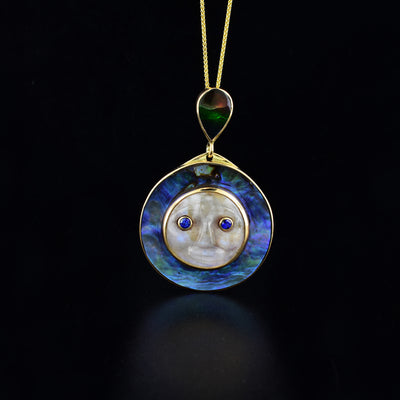 Moon pendant hand-carved by Cree artist Cory BigCharles. Made of moonstone, AAA grade ammolite, abalone, AA grade sapphire and 14K gold. 2" x 1.25" including bail.