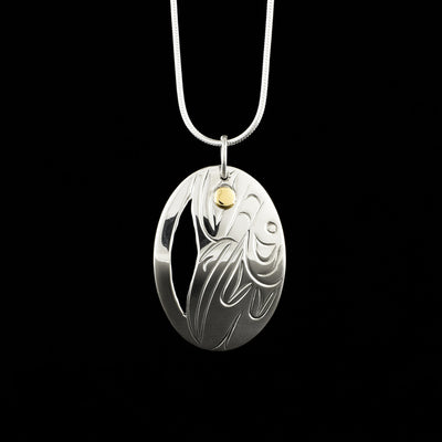 Pendant made of sterling silver and 14K gold. Depicts a side view of a hummingbird's face and wing. 1.63" x 1" including bail. Chain not included. By Indigenous artist Ernie Smith.