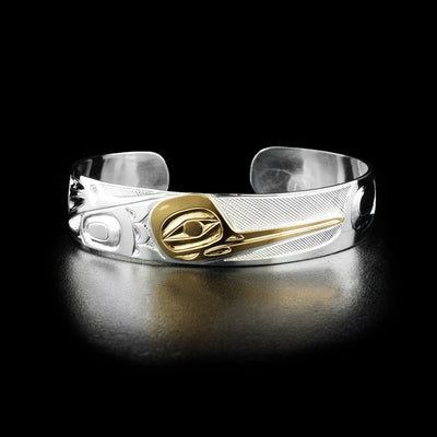 Dazzling hummingbird cuff bracelet hand-carved by Indigenous artist Ivan Thomas. Made of sterling silver and 14K gold. Bracelet is 6.19" long with 0.69" gap and has width of 0.50".