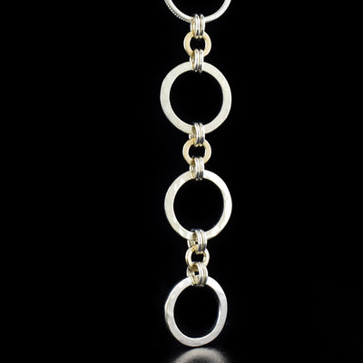 Silver and Gold Kindness Triple Pendant Necklace by artist Lynda Constantine. She has used sterling silver and 14K gold to create the pendant. Sterling silver snake chain included. Chain is 18" long and pendant measures 2.75" x 0.63".