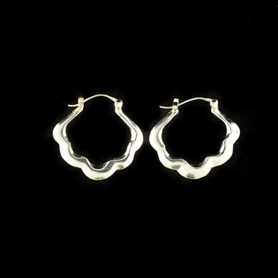 Small blossom hoop earrings handcrafted by artist Victoria Poynton. Made of sterling silver. Each earring measures 1" x 0.9".