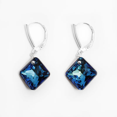 Delicate lever back earrings handcrafted by artist Debra Nelson. Made of sterling silver and Bermuda Blue Swarovski Crystal. Each earring measures 1.38" x 0.60" including hook.