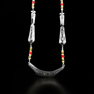 Sterling Silver Canoe with Paddles Necklace hand-carved by Kwakwaka'wakw artist Harold Alfred. Rows of beads after paddles are attached to sterling silver chain. Made of sterling silver and glass beads. Central canoe pendant measures 2.31" x 0.38" and necklace is 22" long.