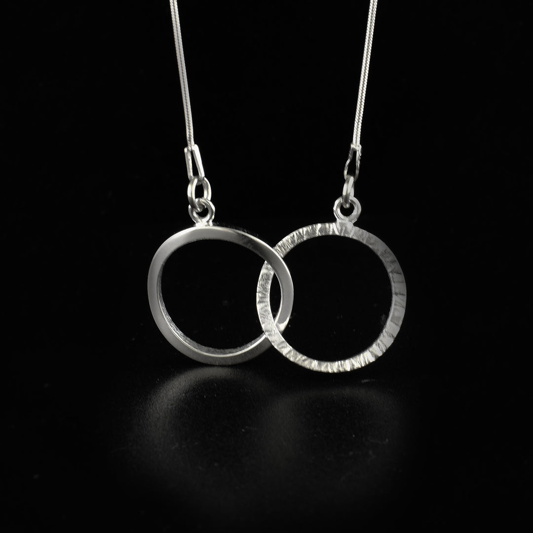 This unique hoop necklace is made form sterling silver and has two thin hoops on either end of the chain. These hoops are interlocked to connect the chain and form the pendant,