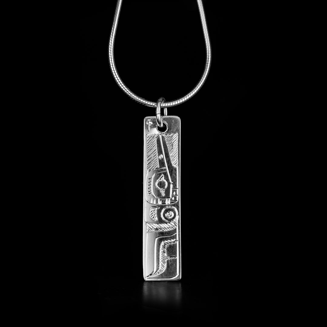 Detailed hummingbird pendant hand-carved by Coast Salish artist Gilbert Pat. Made of sterling silver. Both sides of pendant feature a hummingbird. Pendant measures 1.40" x 0.30" including bail. Chain not included.