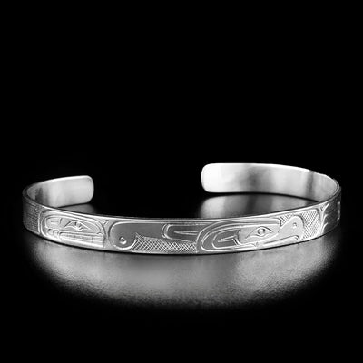 This thunderbird and orca bracelet has the profile of a thunderbird's head facing the right in the center of the bracelet. To the left is the profile of an orca's head.