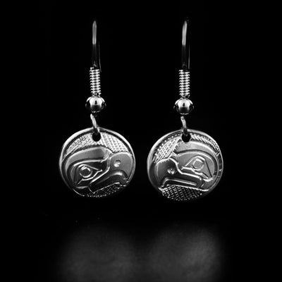 Round mini eagle dangle earrings hand-carved by Kwakwaka'wakw artist Norman Seaweed. He has used sterling silver to create them. Each earring measures 1.13" x 0.50" including hook.
