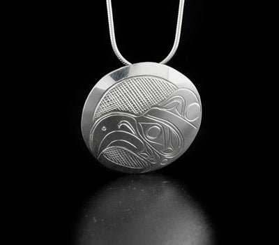 Round thunderbird pendant hand-carved by Kwakwaka'wakw artist Don Lancaster. Made of sterling silver. Pendant is 1.25" in diameter. Hidden bail on back. Chain not included.