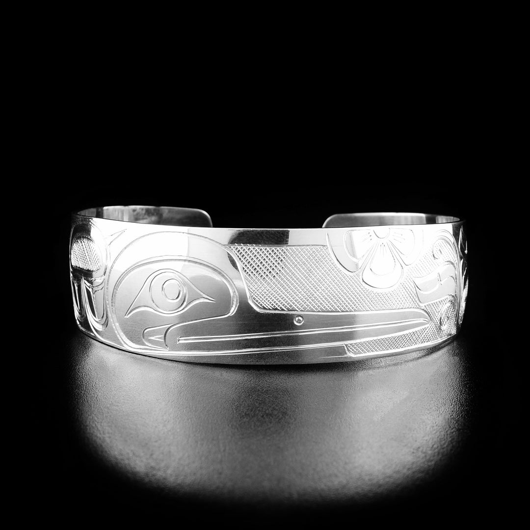 This hummingbird bracelet has the profile of a hummingbird's head with a long, narrow beak facing the right in the center of the bracelet. Flowers are surrounding the legend.