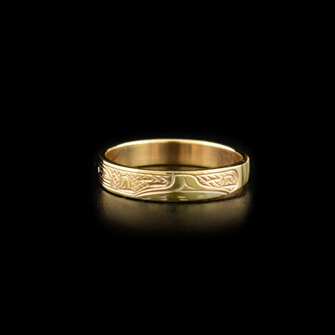 Right angle photo of the gold ring shows the bodies and dorsal fins of multiple orcas depicting a pod.
