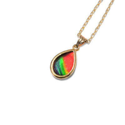 This ammolite pendant is teardrop shaped and has the colours red, yellow, green, and blue encased in 14k gold.