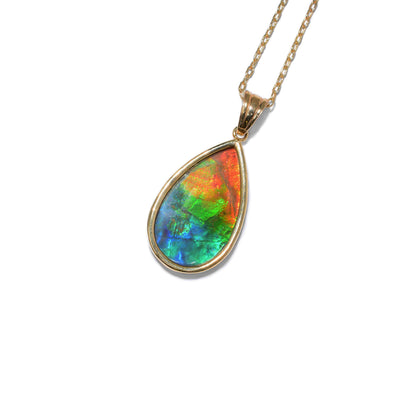 This ammolite pendant is teardrop in shape and has a triangular bail. It has a mix of orange, red, green, and blue colours.