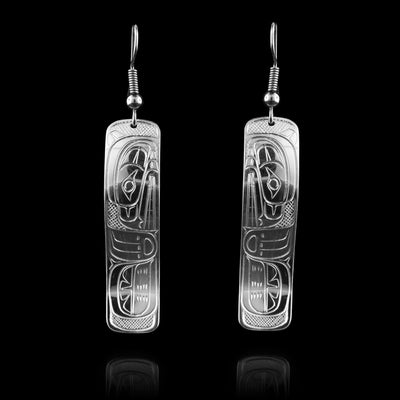 These rectangle dangle earrings have long, rectangle hangs with rounded edges that are made from sterling silver. a depiction of the Bear legend is carved into the hangs. The head of the Bear is at a side profile and looking downward with its paw at the bottom of the piece. The hangs have been bent to have a wavy shape.