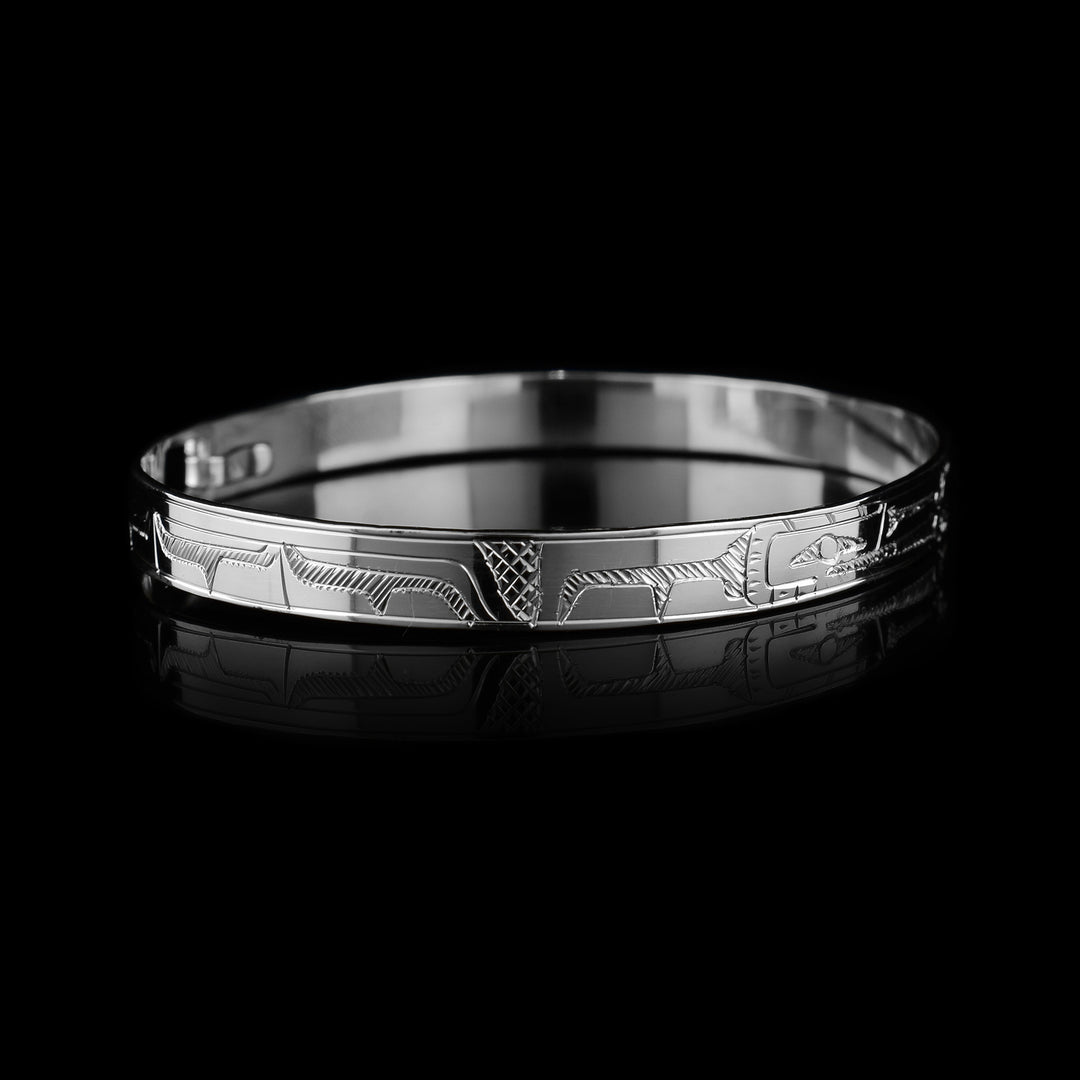 These sterling silver bangle bracelets have a single, thin band with a clasp in the back. There are carvings of the Raven and the Hummingbird legends, one on either side of the band. The birds are depicted as a side profile with their heads meeting in the center of the band.