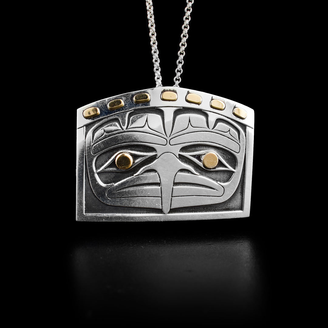 This beautiful Eagle pendant is made from sterling silver and has 14K gold highlights. The pendant is rectangle shape with a domed top. The piece shows the head of the eagle facing foreword. The eyes of the eagle are gold and there are gold studs at the top of the dome above the eagle's head.