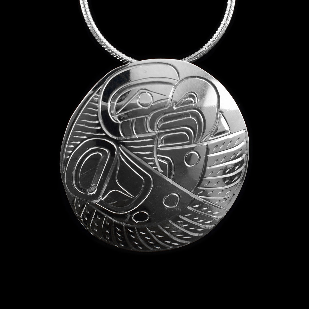 This Eagle silver pendant has a circle shape and is made from sterling silver. There is a depiction of the Eagle carved at a side profile with intricate details. You can see both of its wings with feather details and its eye and beak are included.