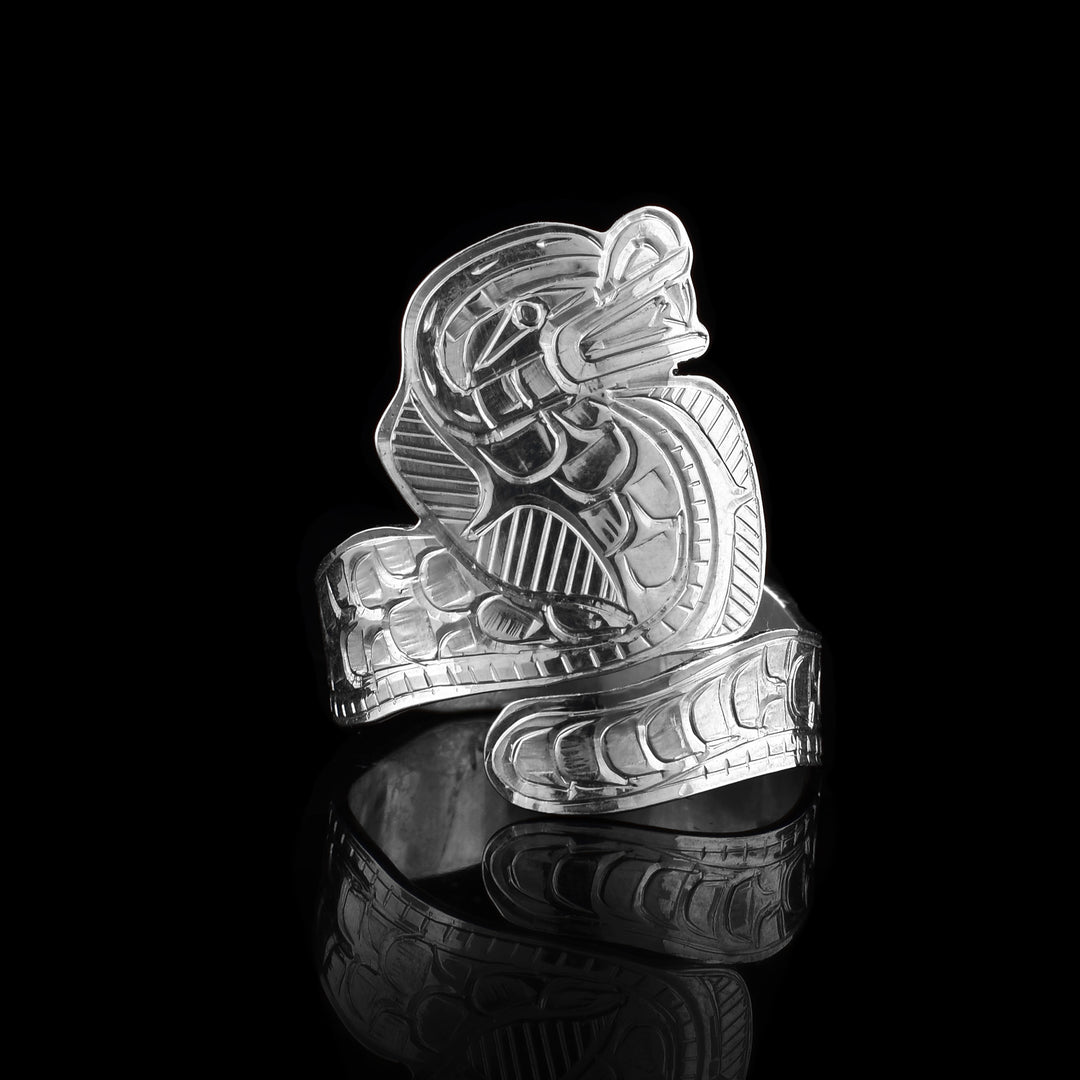 This snake wrap ring is made from sterling silver and is shaped like a cobra that wraps around the finger twice. There are carvings representing scales and the head of the snake is standing up. You can see teeth details carved into it.