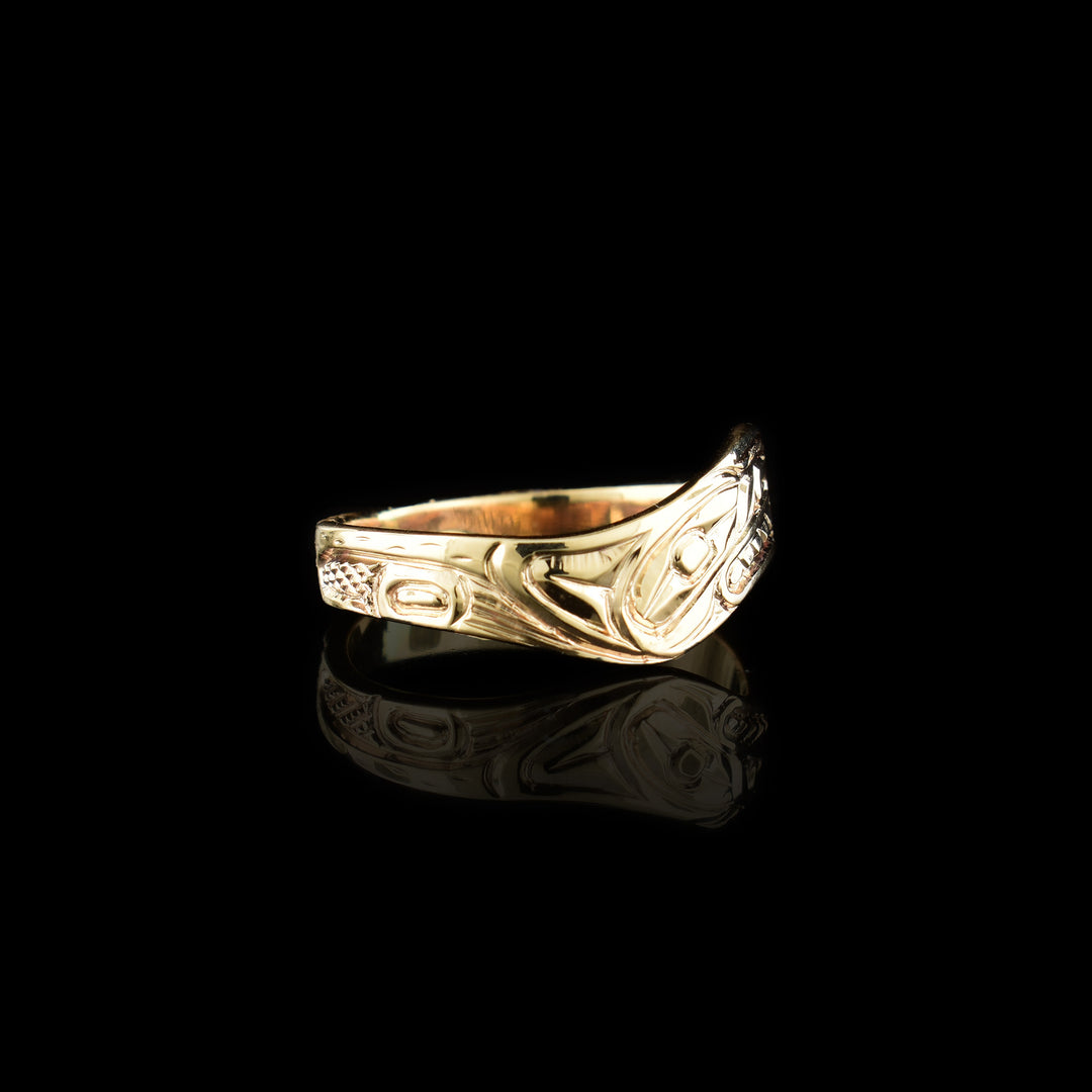 This wavy band ring has a thin, 14K gold band with a wavy appearance. There is a depiction of a side view of the head of the Wolf carved into the surface of the band. Around the head, other details of the Wolf are carved.