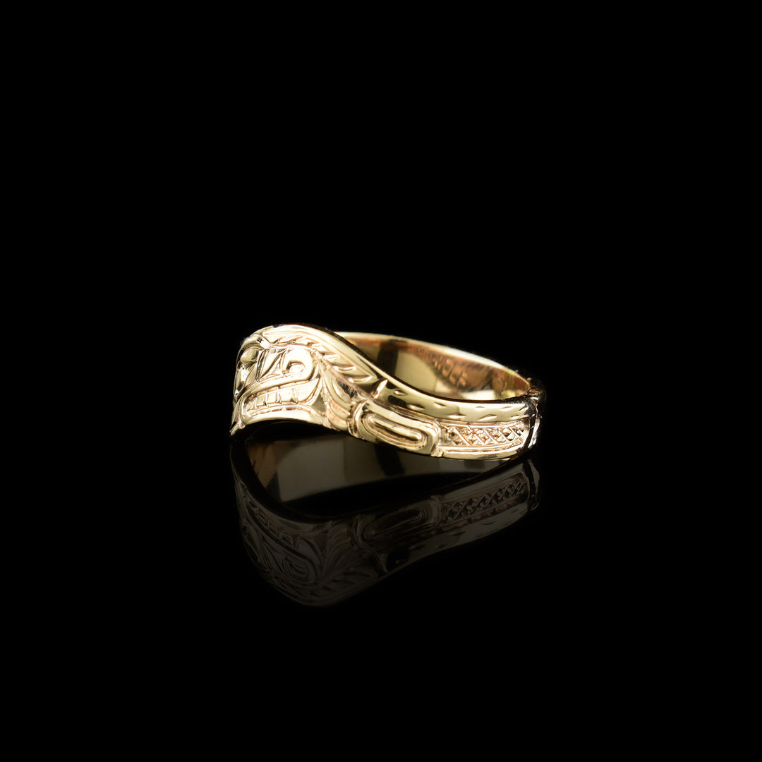 This wavy band ring has a thin, 14K gold band with a wavy appearance. There is a depiction of a side view of the head of the Wolf carved into the surface of the band. Around the head, other details of the Wolf are carved.
