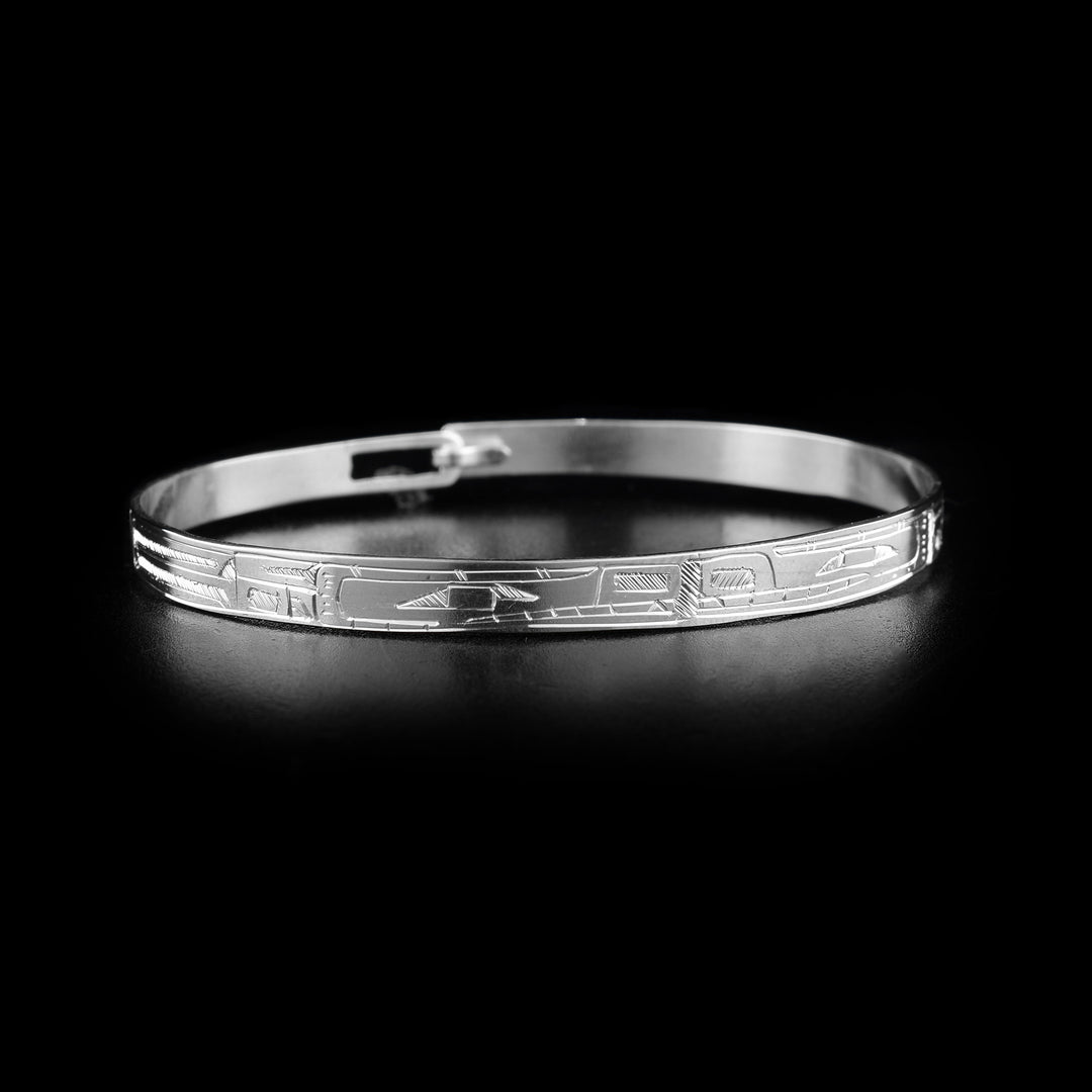 This sterling silver cuff bangle bracelet has a thin band with a clasp in the back. There are two Bear legends carved into the surface of the band. Their heads meet at the front of the piece and their bodies extend around the rest of it.