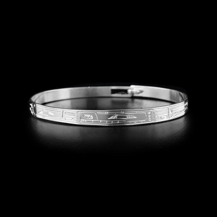 This sterling silver cuff bangle bracelet has a thin band with a clasp in the back. There are two Bear legends carved into the surface of the band. Their heads meet at the front of the piece and their bodies extend around the rest of it.