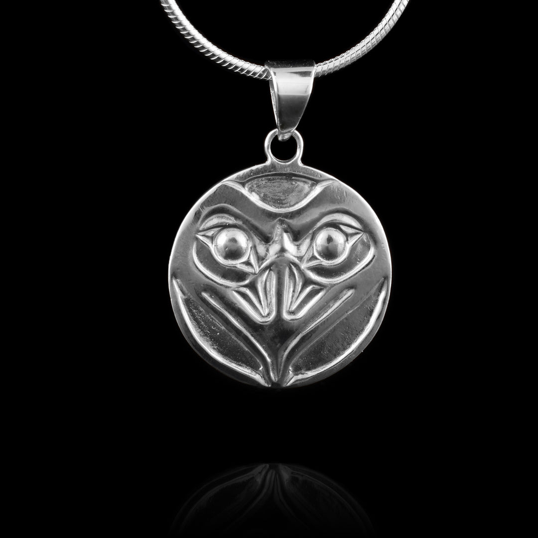 This Raven pendant is made from sterling silver and is circle shaped. The piece shows the face of the Raven  facing out with both its eyes and large, sharp beak detailed. 
